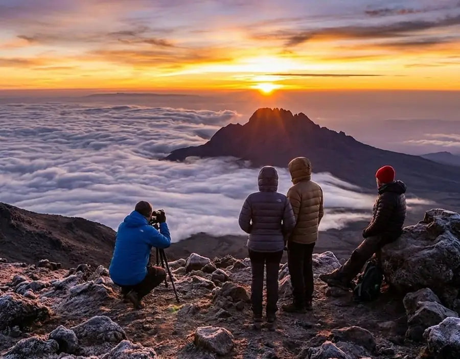 Climbers standing at Uhuru Peak summit of Mount Kilimanjaro with Baba Kilimanjaro